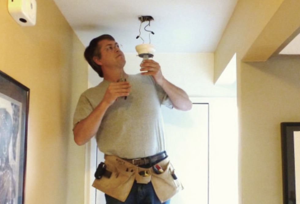 Scott installing a ceiling light fixture in a home