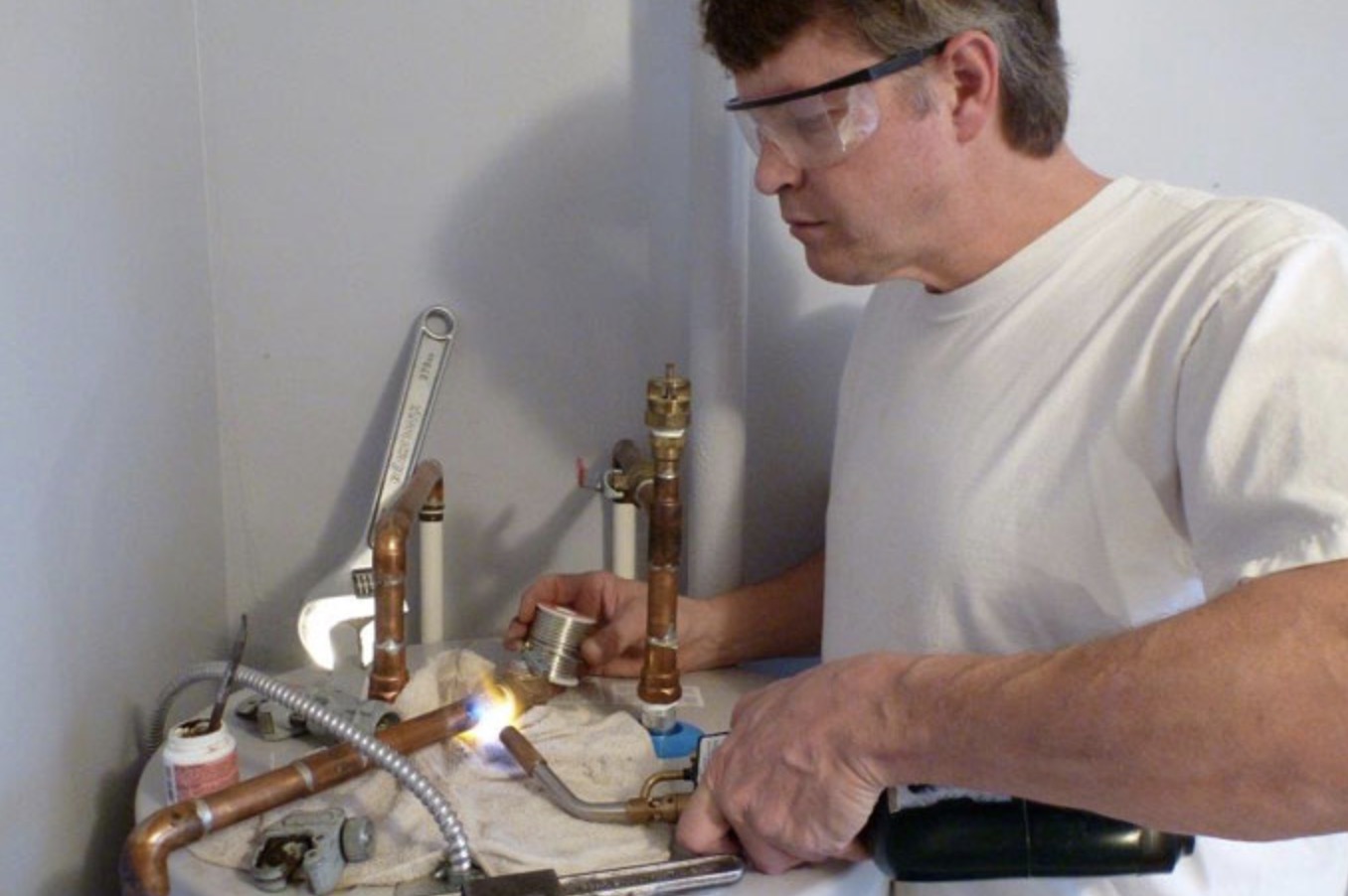 Scott soldering copper pipe fittings during a plumbing repair